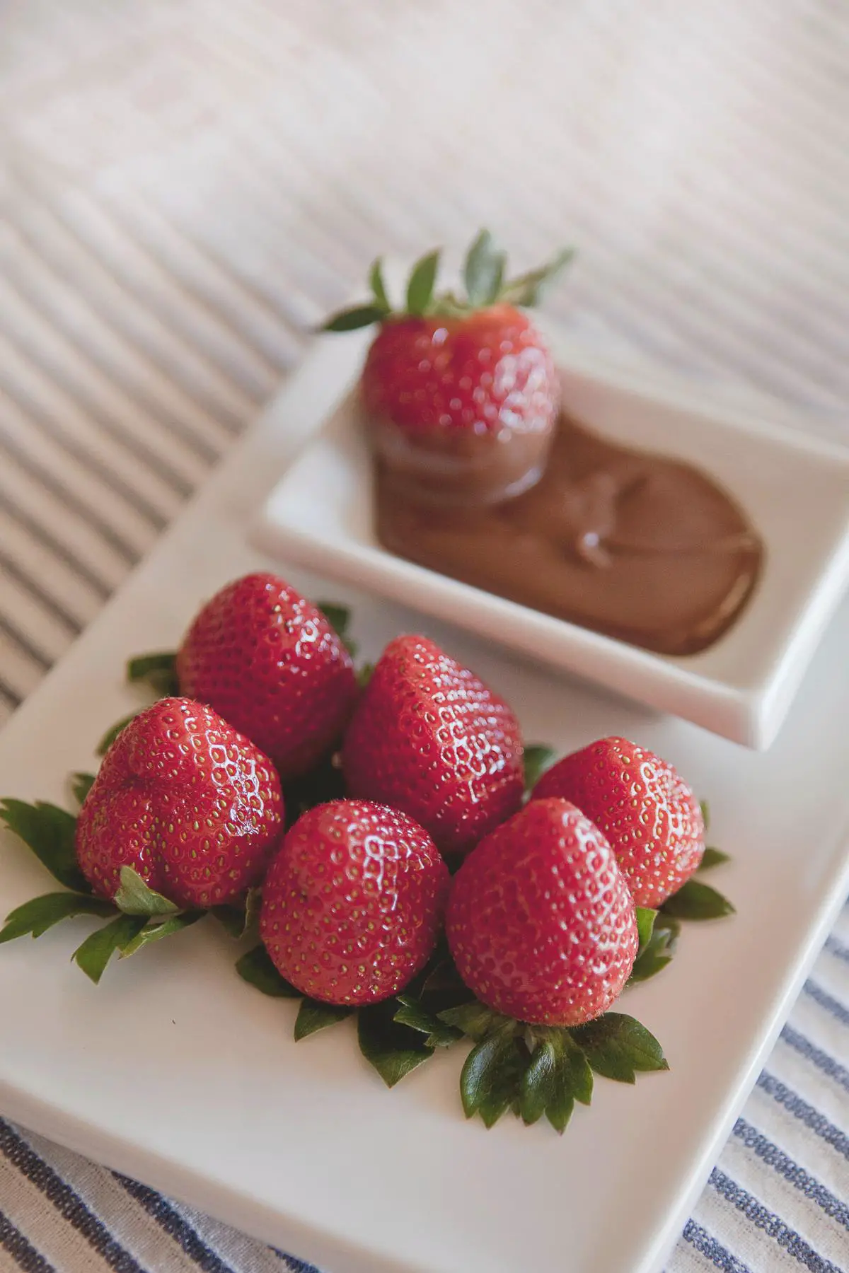 A plate of chocolate-covered strawberries with a drizzle of dark chocolate on top, perfect for a family dessert.