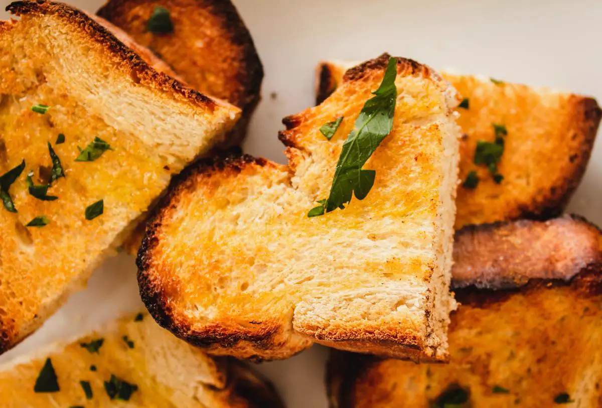 Image of a slice of Costco's garlic bread, showcasing its crusty exterior and soft interior with a flavorful spread of garlic and herbs.