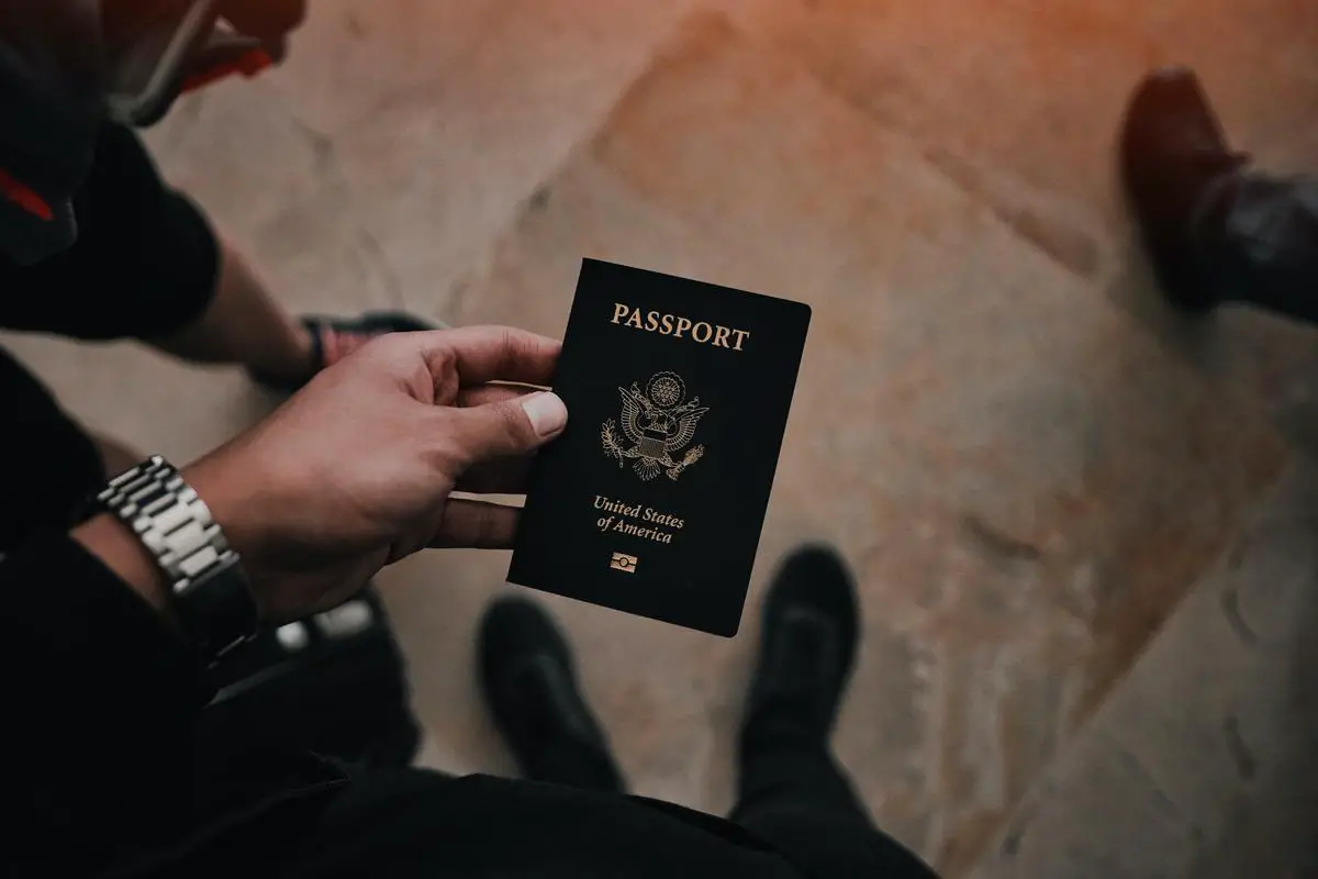 Image of a person holding a passport with a Costco logo in the background for illustrating Costco's passport photo service.