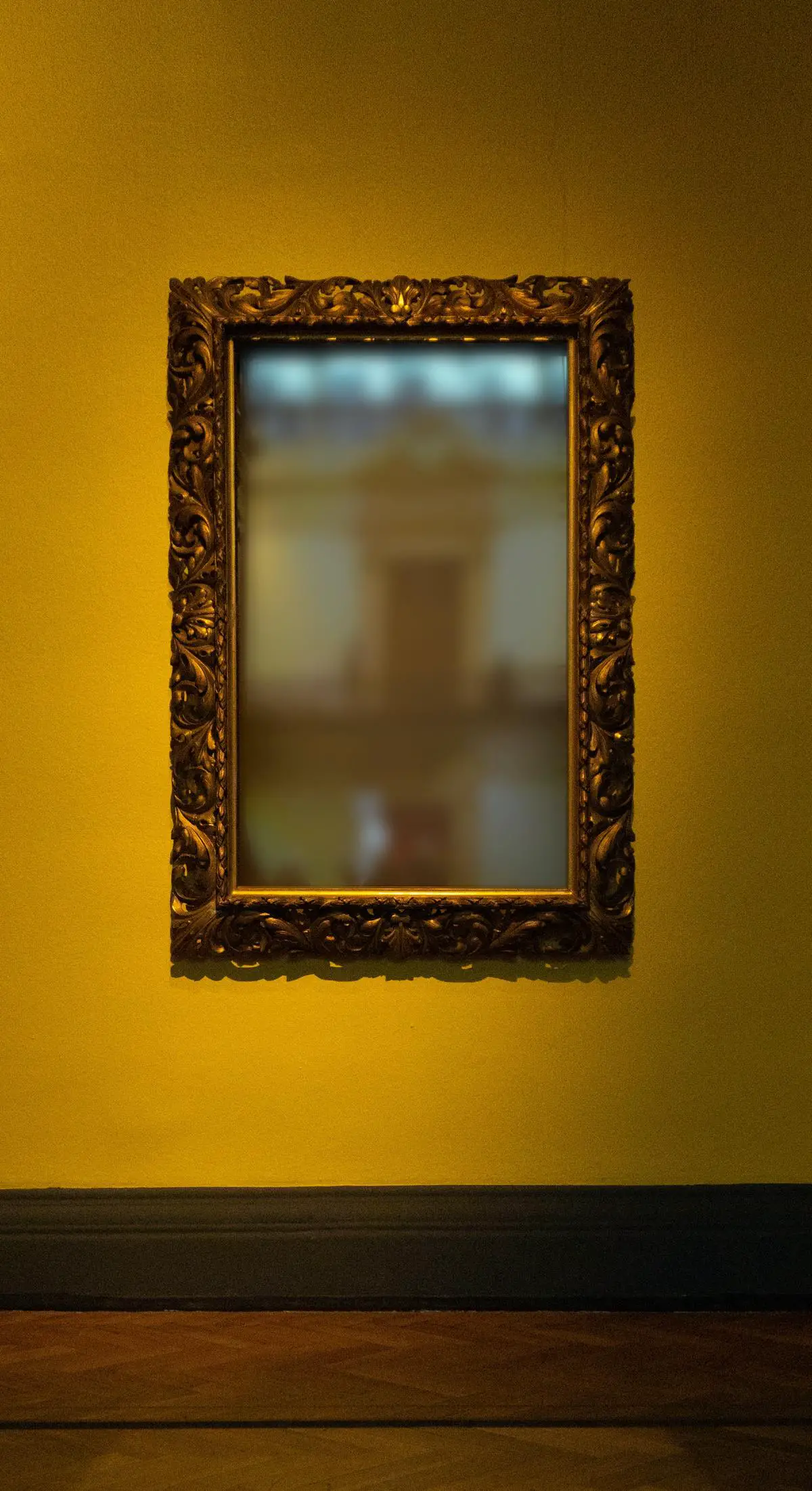 A DIY IKEA Hovet mirror frame made of wood and stained in a dark color sits against a white wall
