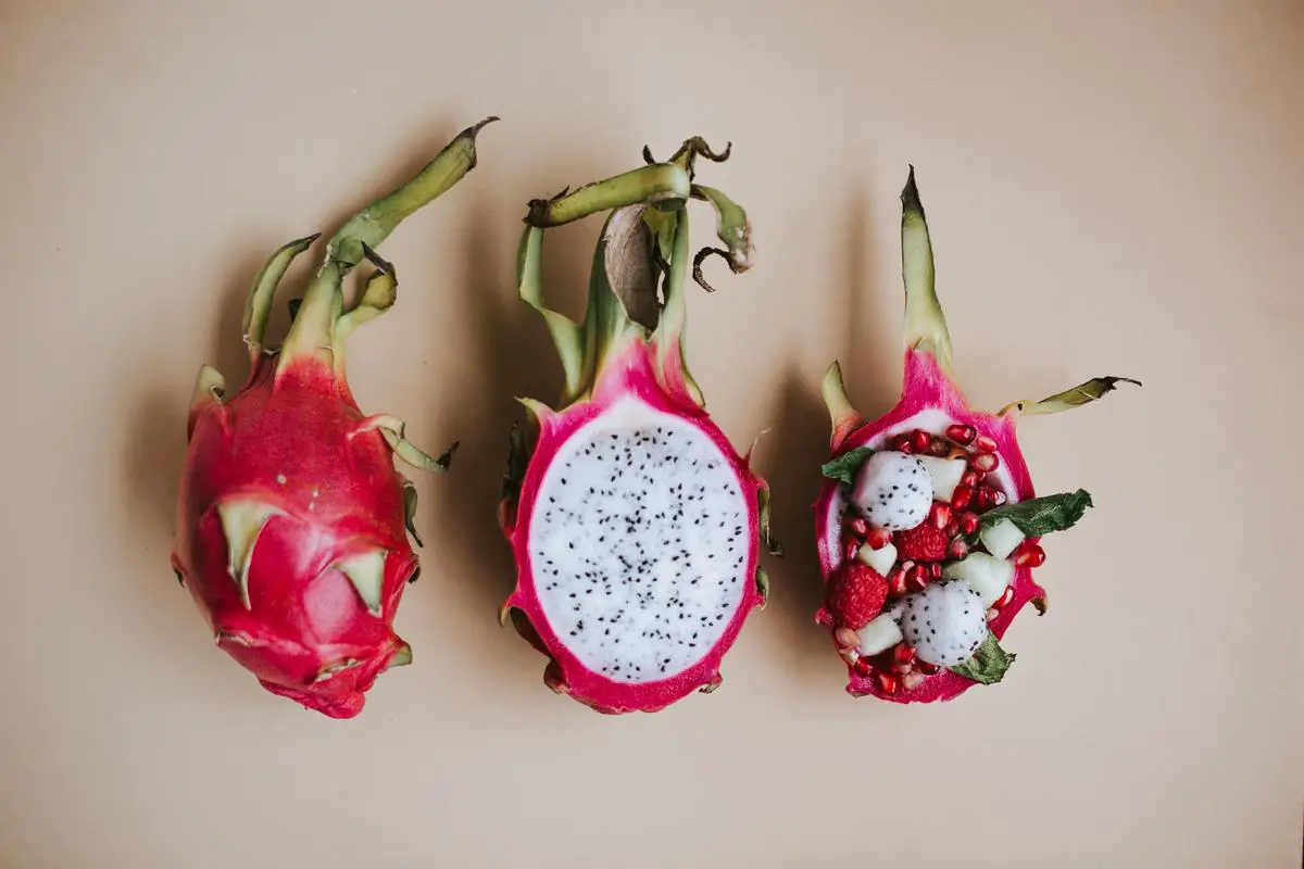 A vibrant red dragon fruit sliced open, showcasing its seed-speckled pulp.